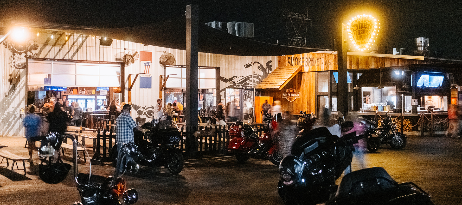 People and motorcycles outside the Shed BBQ at night as the event winds down.