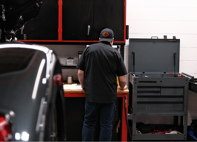 Mechanic standing at a workbench in the service department at Harley-Davidson of Madison, with tool cabinets visible nearby