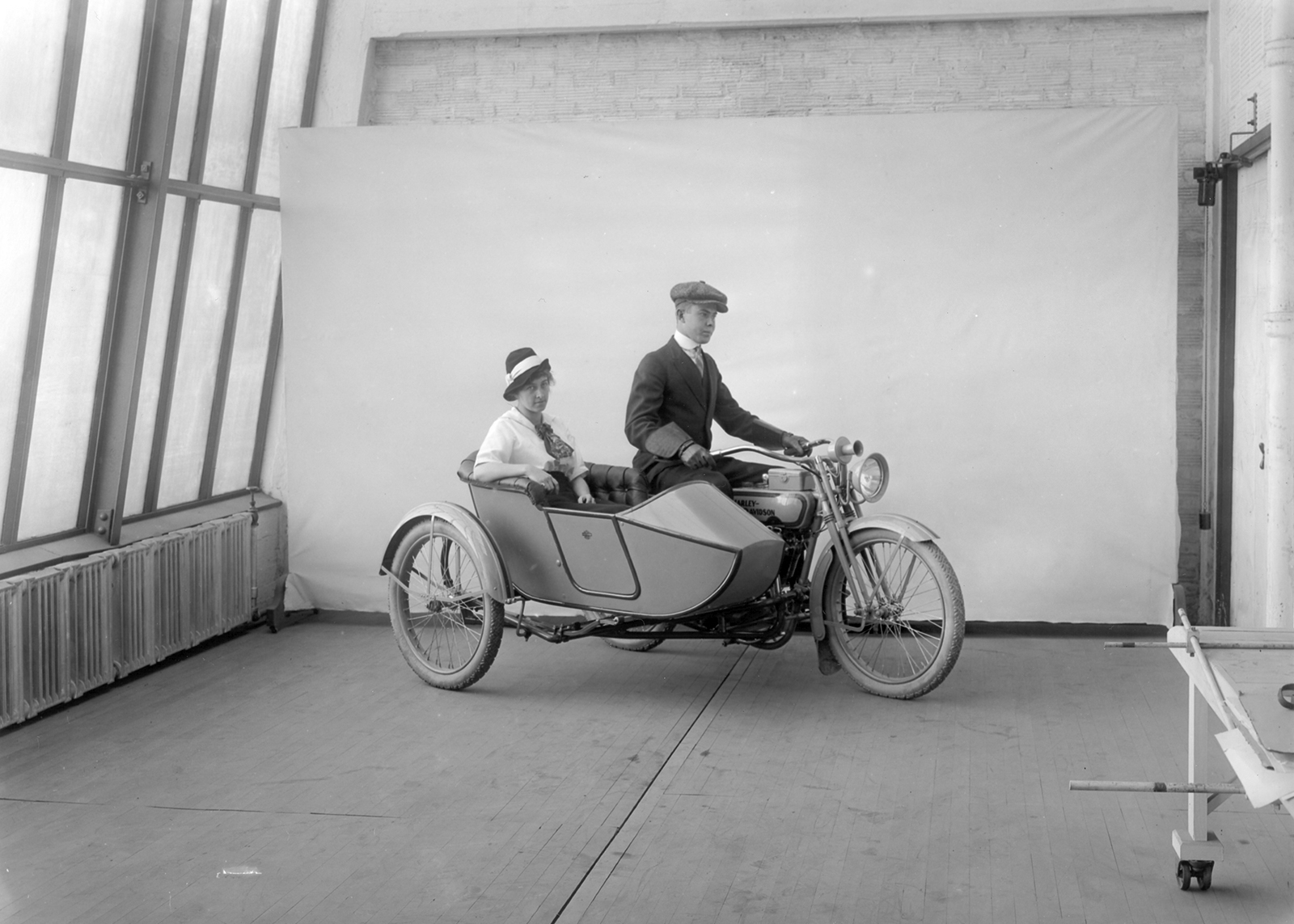 A man and a woman in a motorcycle and sidecar inside a brick room