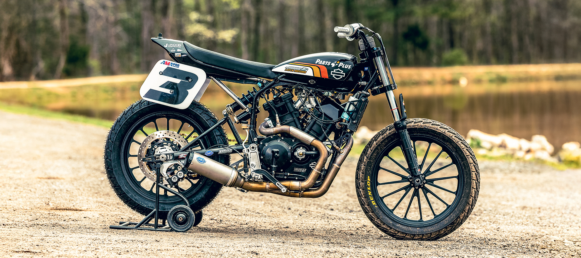 A side profile of Briar Bauman’s number 3 race built Harley-Davidson XG750R with a forest and lake in the background