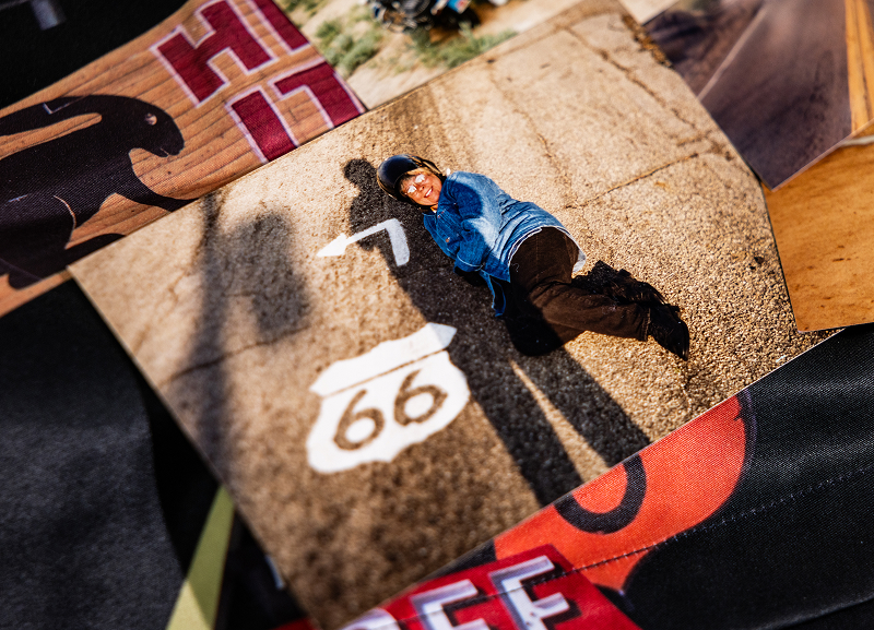 Vintage photo of person lying on pavement next to a painted Route 66 marker