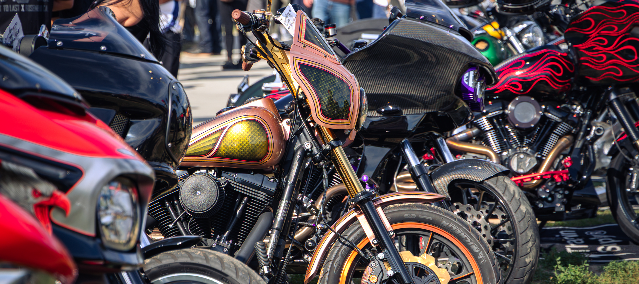 Custom motorcycles with vibrant paint and fairings lined up outdoors at a bike show
