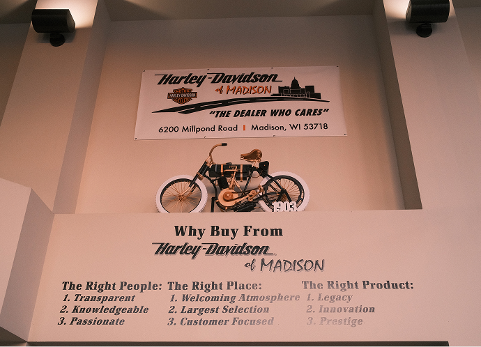 Interior wall display at Harley‑Davidson of Madison featuring a vintage motorcycle model and dealership values signage