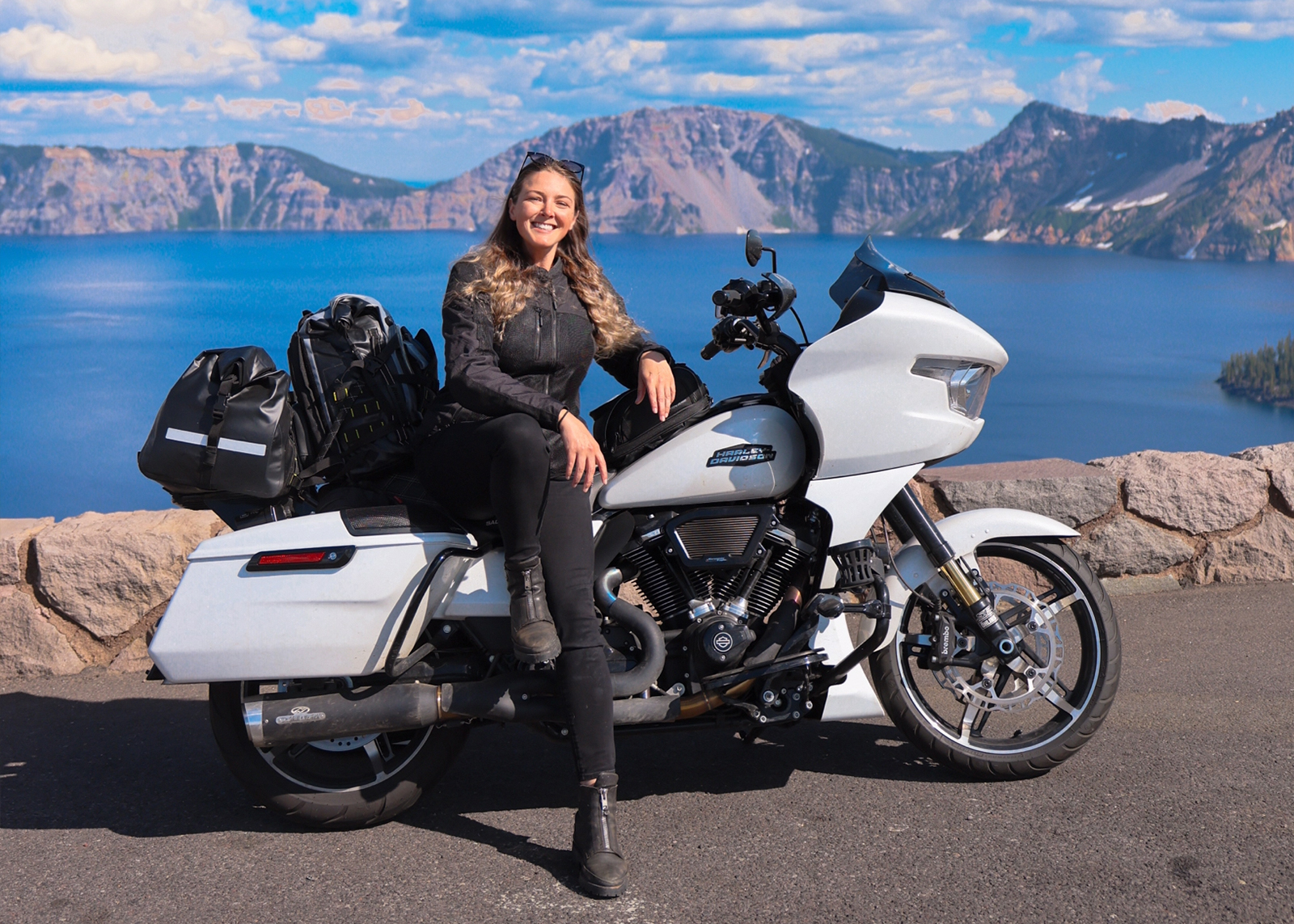 The author sits on her white Harley-Davidson Road Glide motorcycle at Crater Lake National Park.