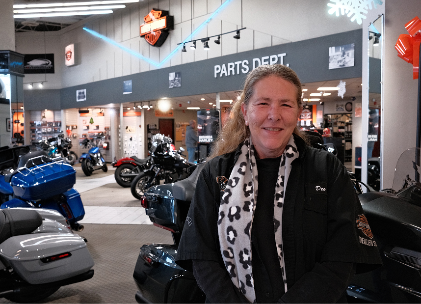 An employee wearing a leopard print scarf poses for a photo in the showroom of Kegel Harley-Davidson