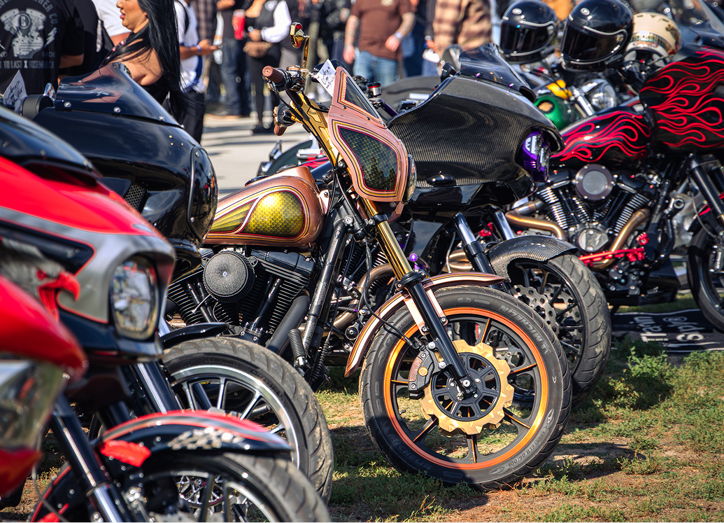 Custom motorcycles with vibrant paint and fairings lined up outdoors at a bike show