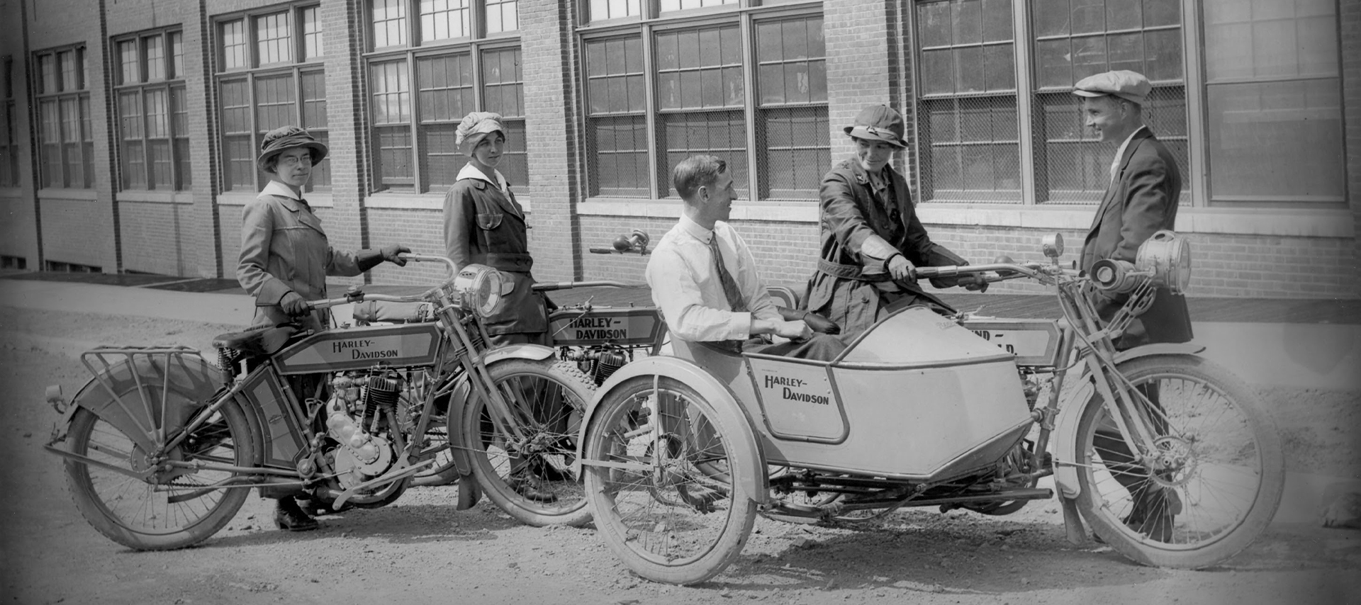 Two motorcycles and sidecars are parked with various people around them 