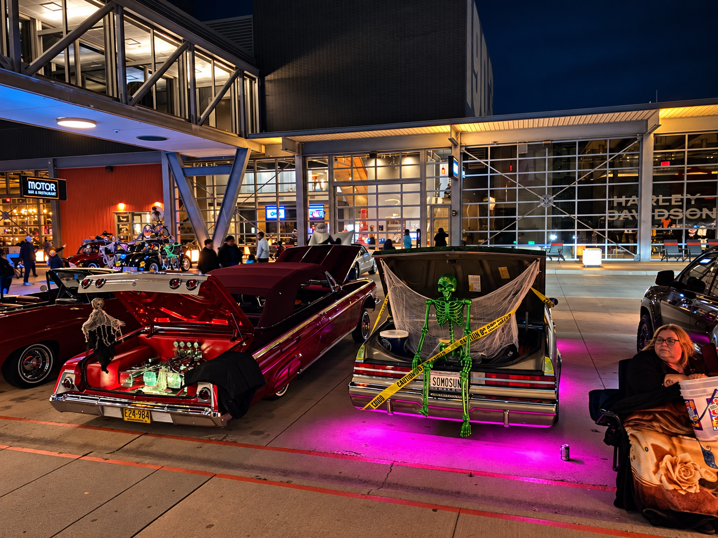 Halloween-themed classic car display outside Harley-Davidson Museum at night