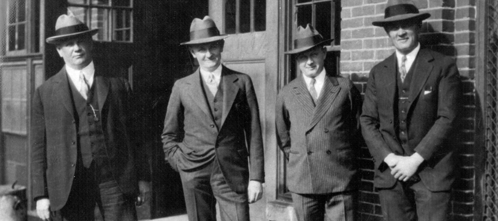 The four H-D founders pose outside of a building