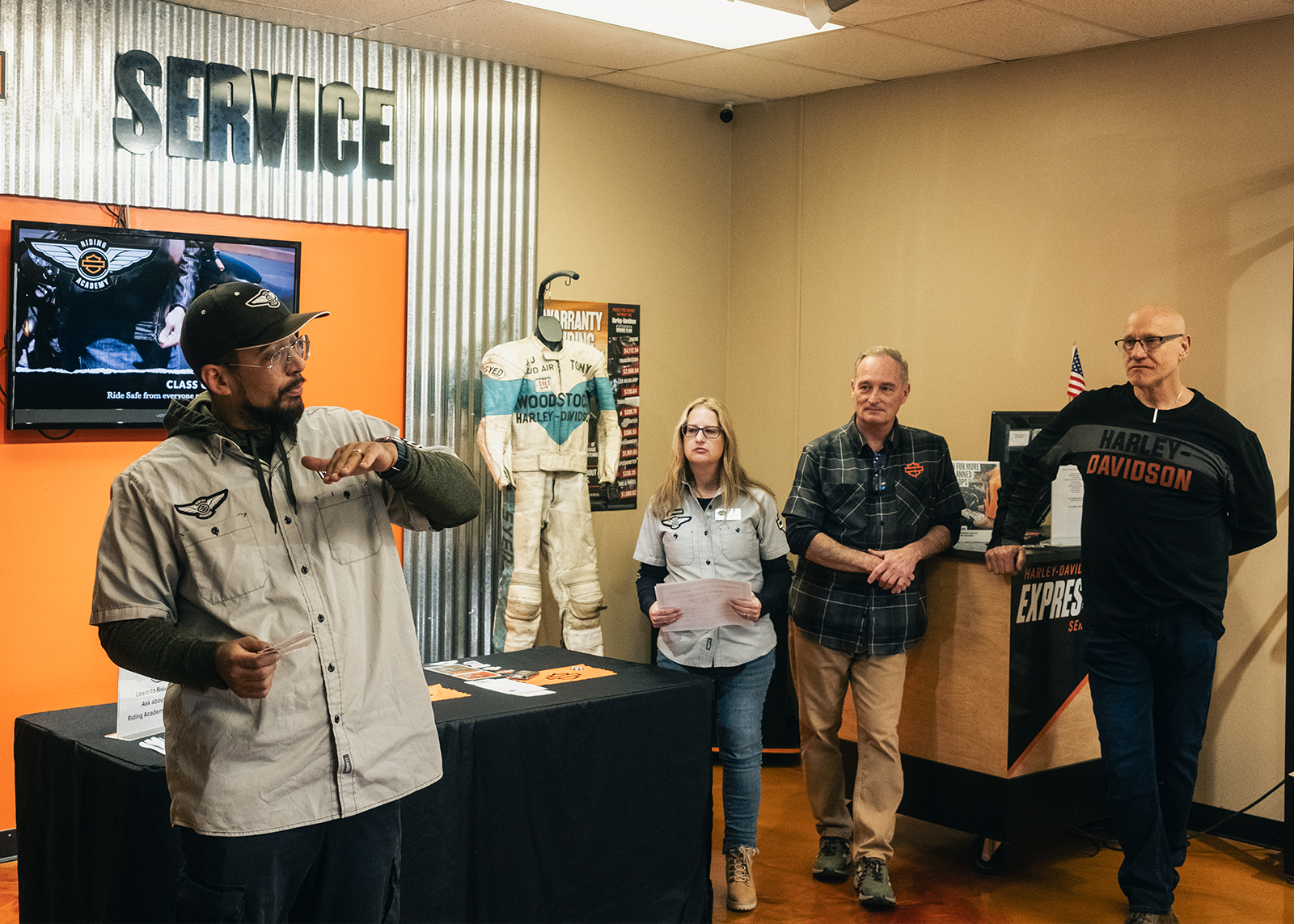 H-D® Riding Academy instructor provides guidance to students as three staff members look on.
