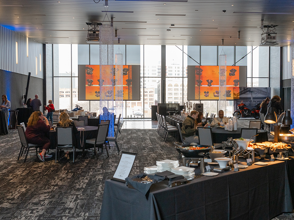 Guests dining at tables with buffet setup in Harley-Davidson event hall