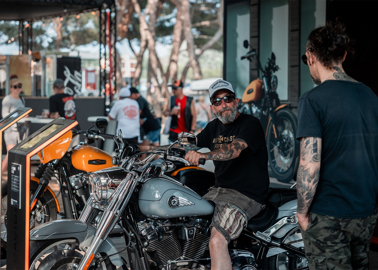Person sits on custom cruiser motorcycle at outdoor bike show
