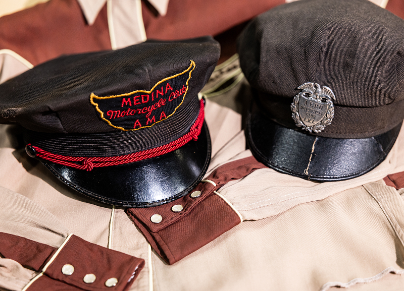 Vintage motorcycle club caps displayed on embroidered riding shirts with western-style details
