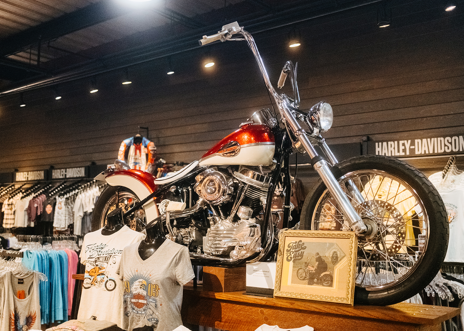 A 1954 FL Panhead Chopper on display, surrounded by t-shirts and apparel.