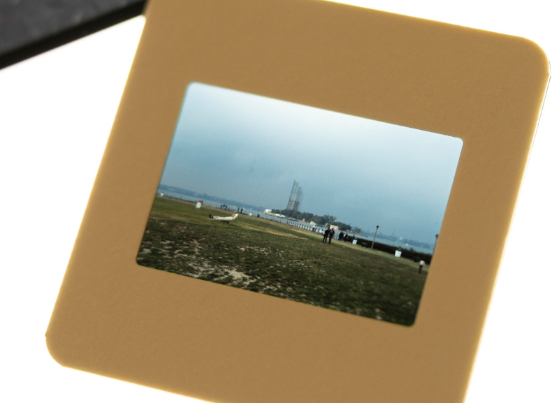 Mounted color slide showing the Statue of Liberty under scaffolding in the distance viewed through a slide frame