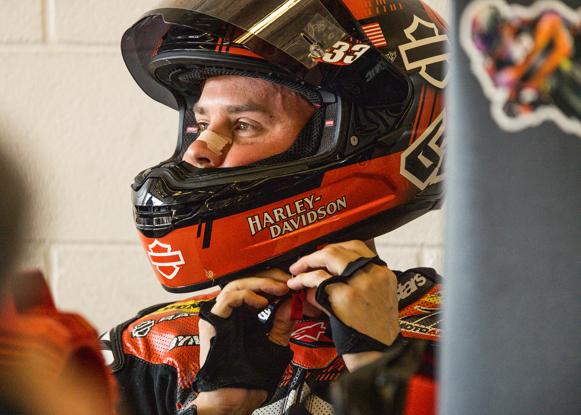 A close up portrait of Kyle Wyman clipping into his helmet before a race.
