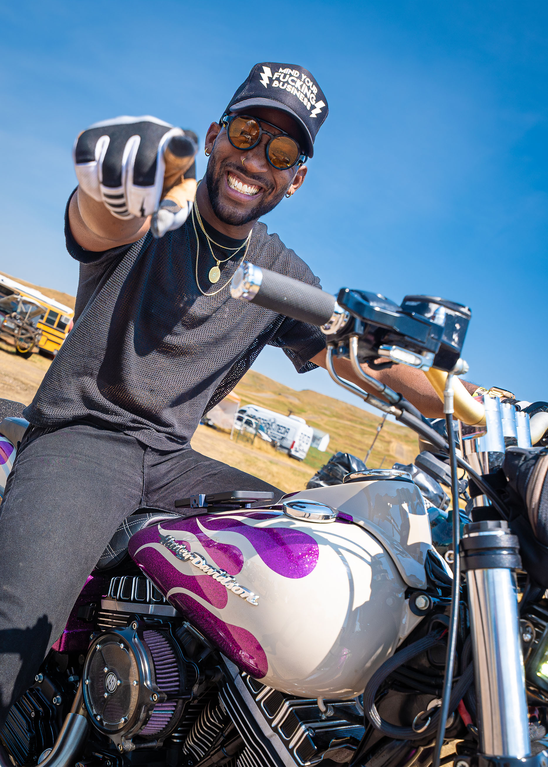 A man on a motorcycle points at the camera 