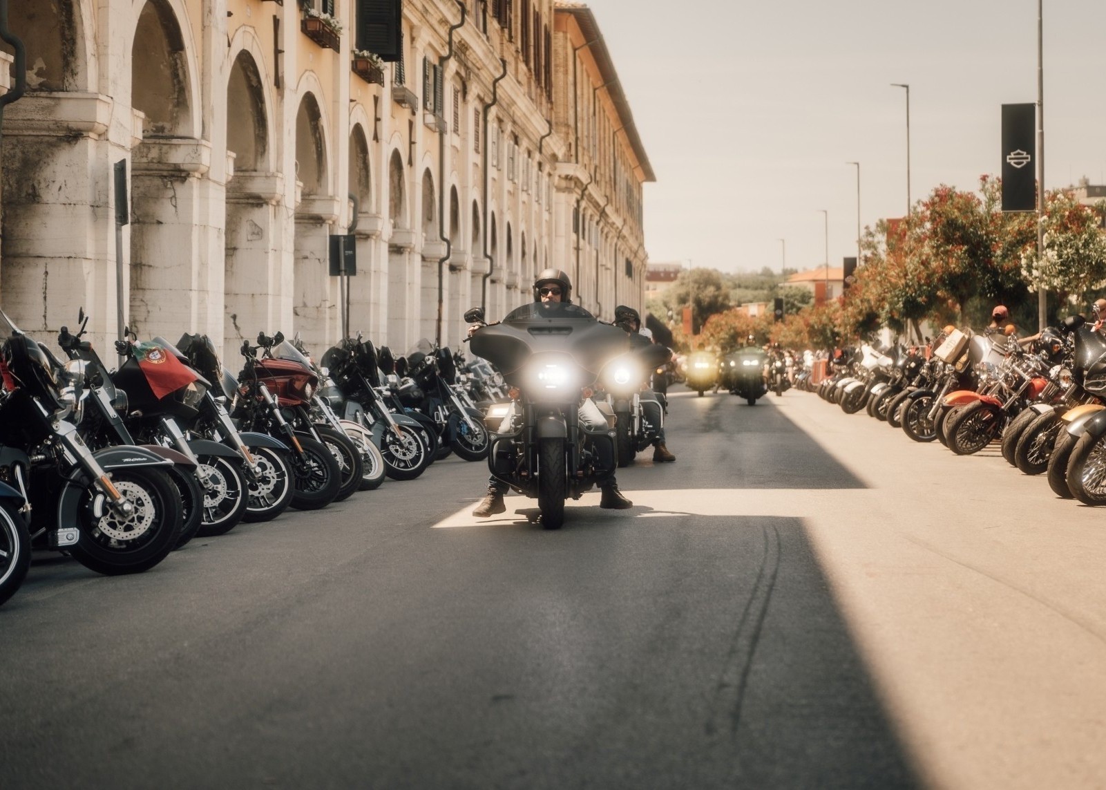 Motorcycles riding through Senigallia Spring Rally with bikes parked along both sides of the road.