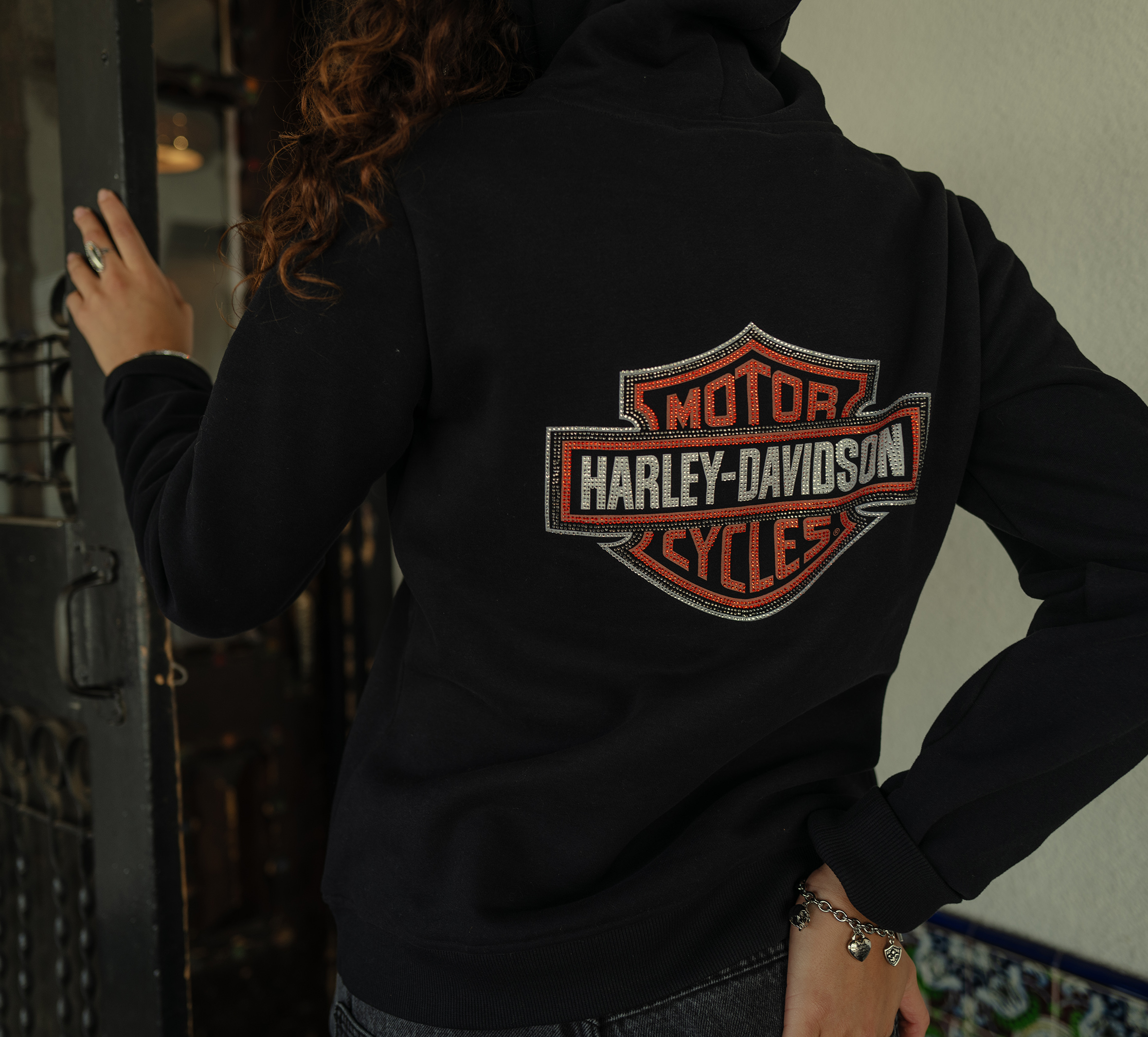 back of woman wearing black hoodie with bling bar and shield logo