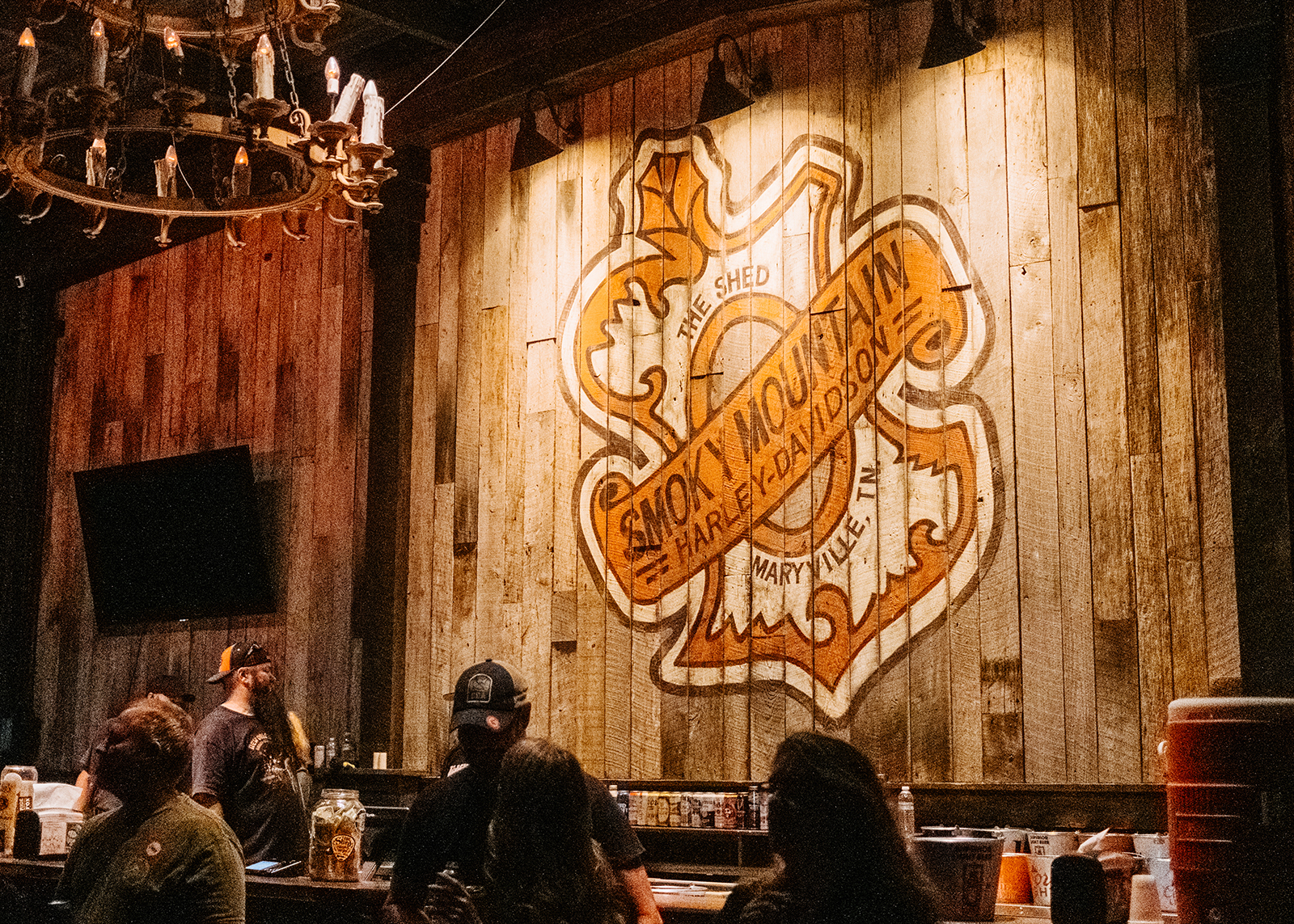 A Smoky Mountain Harley-Davidson motif is painted on rustic wood in the dimly lit Shed BBQ.