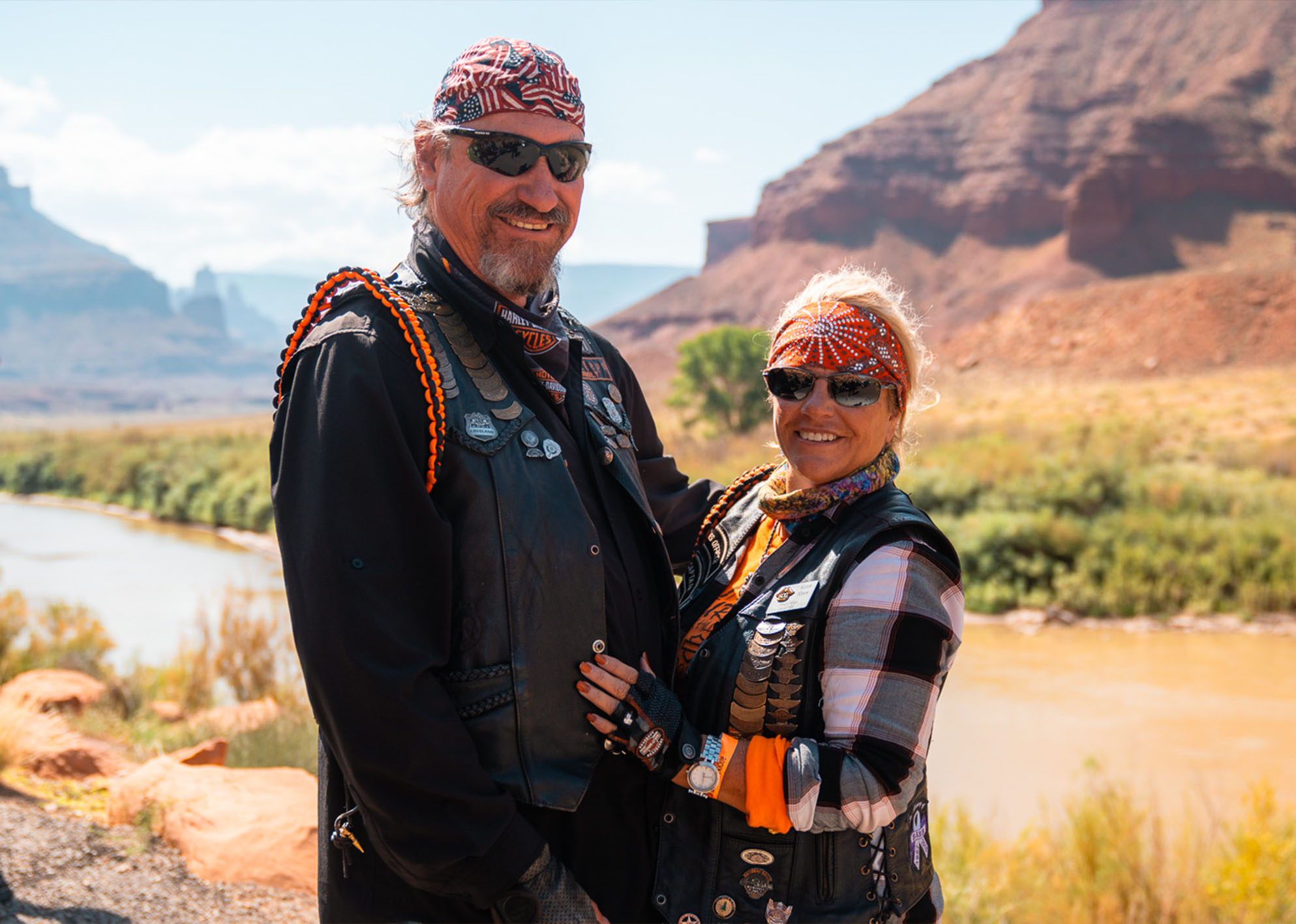 A man and woman pose for a photo next to a riverbank