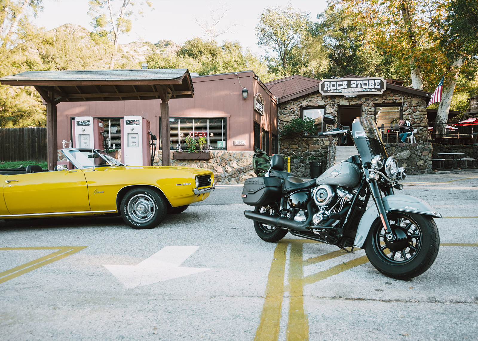 A Harley-Davidson Heritage Classic motorcycle parked next to a classic yellow Camaro at the Rock Store