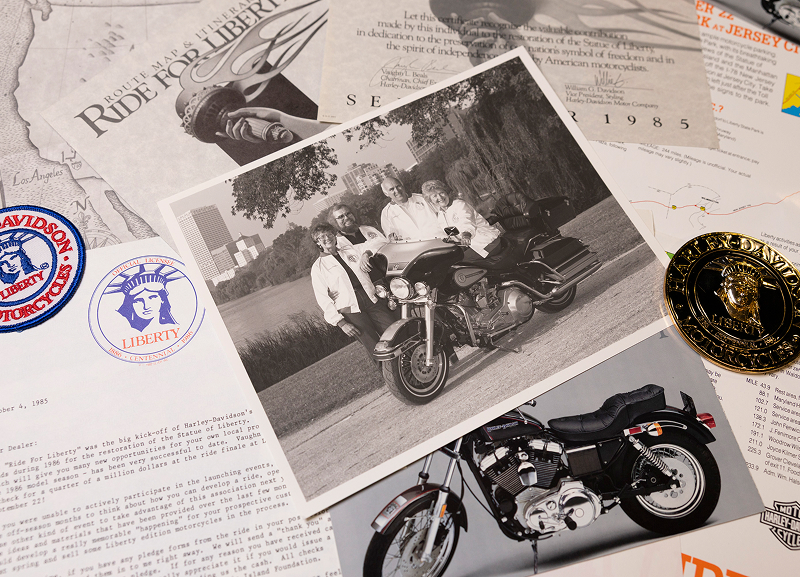 Archival photo of Willie G. Davidson and CEO Vaughn Beals with other Ride For Liberty memorabilia laid out on a table