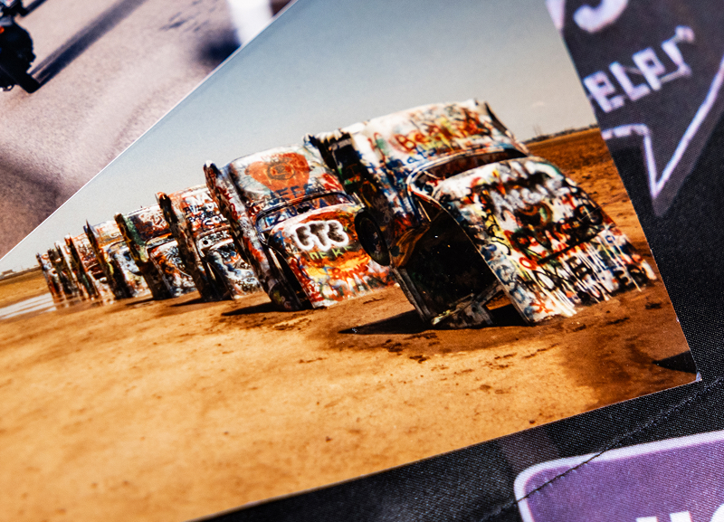 Vintage photo of public art installation Cadillac Ranch - a row of ten old Cadillacs buried nose-first in the ground and covered in grafitti