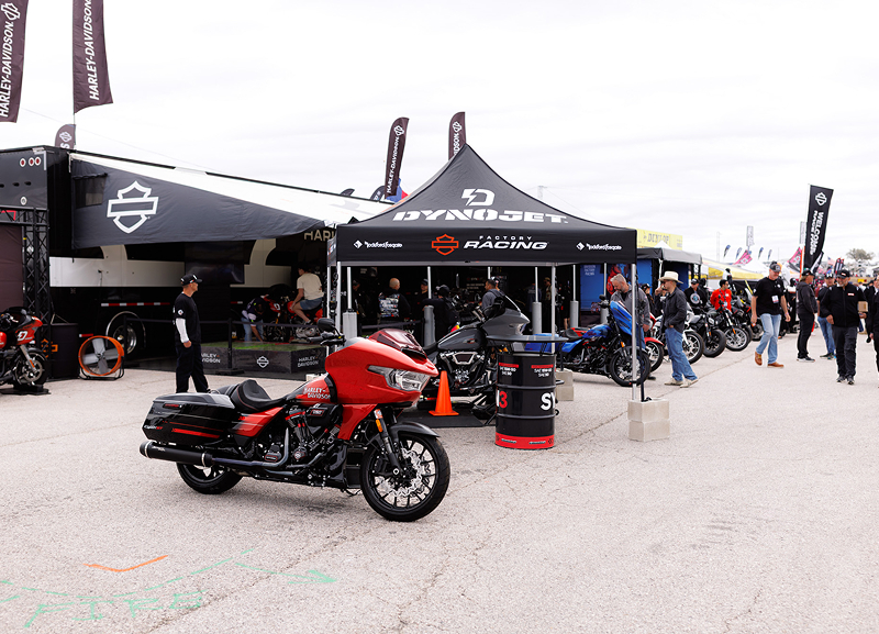 Harley-Davidson racing tent in the paddock with a red motorcycle parked out front and spectators nearby