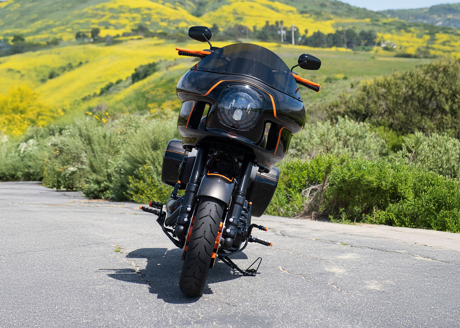 Laidlaw’s custom built motorcycle, The Laidlaw Coastglide, seen from the front with rolling green hills in the background.
