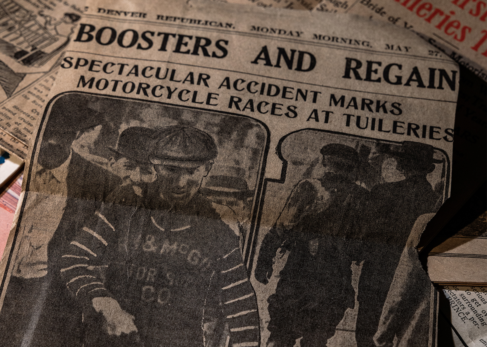 Vintage newspaper clipping with photo of racers and headline “Spectacular Accident Marks Motorcycle Races at Tuileries”