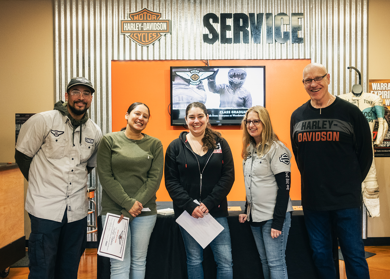 Two graduates of the H-D Riding Academy pose with instructors and staff after receiving their certificates of completion.