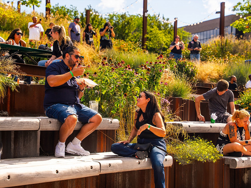 People seated on terraced steps in a garden, eating and talking