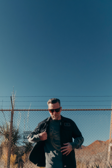 man wearing dickies shirt in front of fence