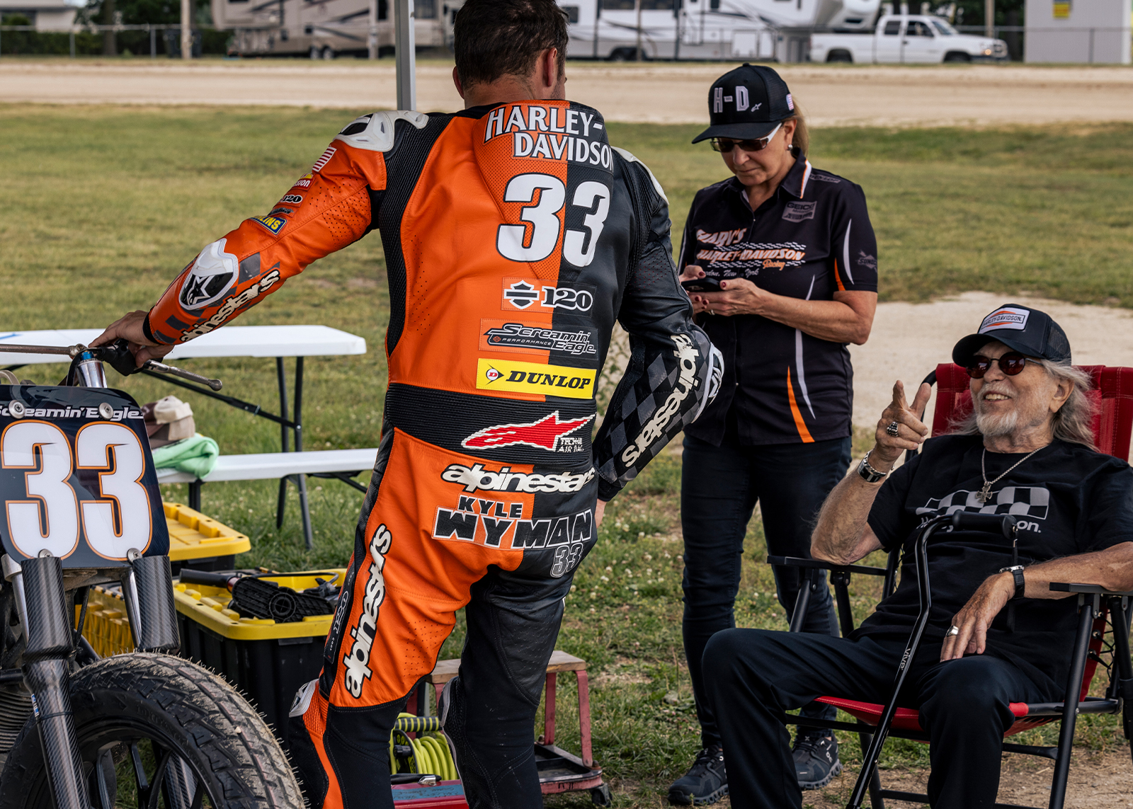 Kyle Wyman in his number thirty-three leathers talks to Willie G under a tent
