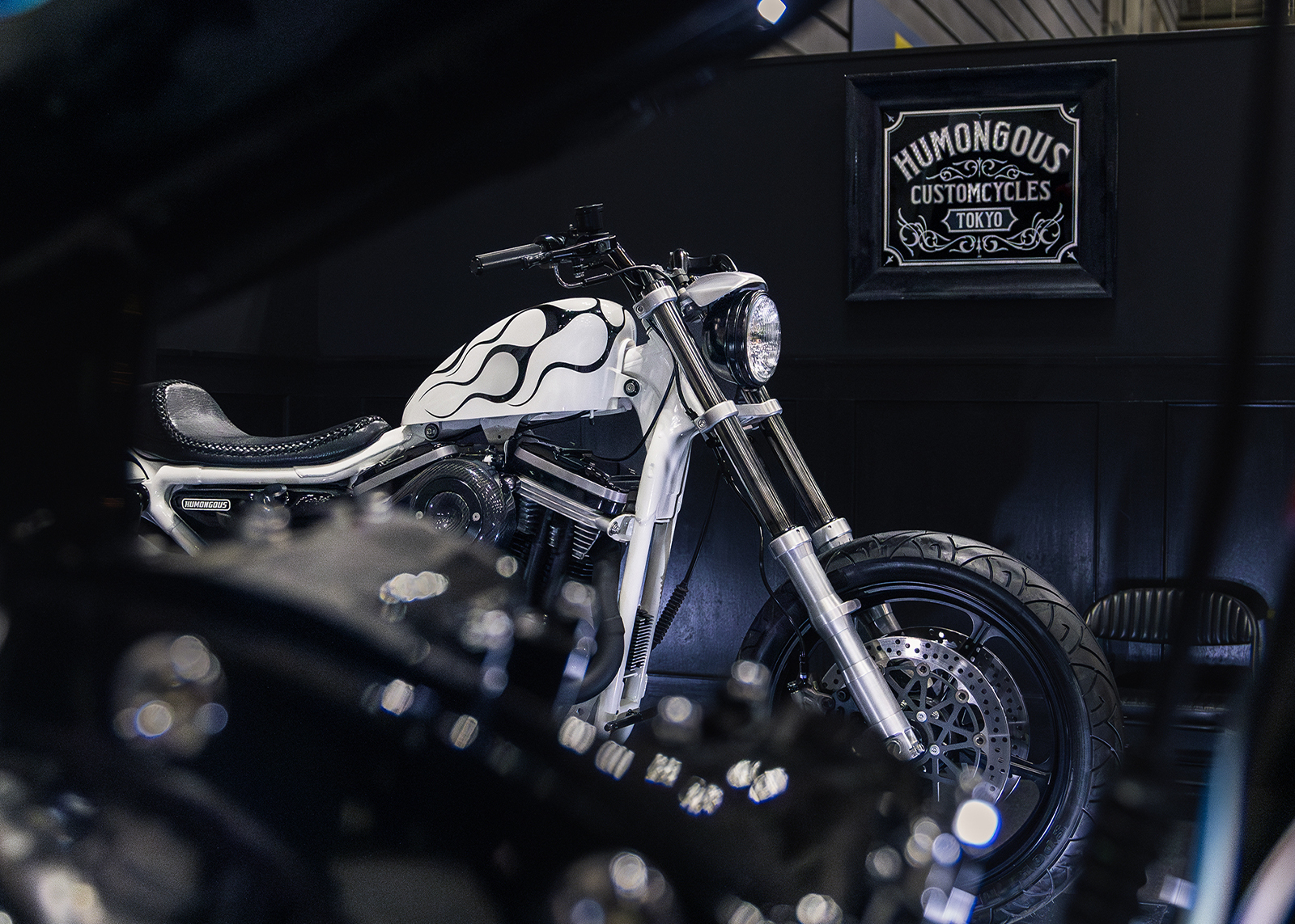 A custom motorcycle on display with white paint and black flames built by Humongous Custom Cycles Tokyo