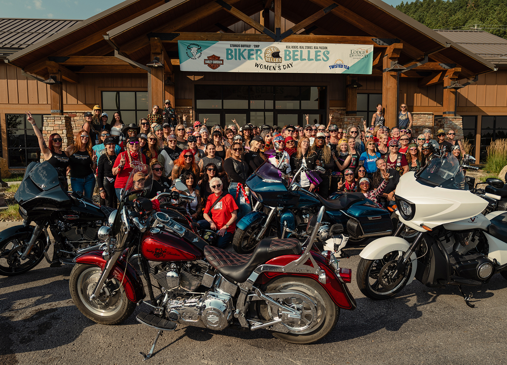 Large group of riders gathers with motorcycles outside a Biker Belles event during Sturgis Motorcycle Rally