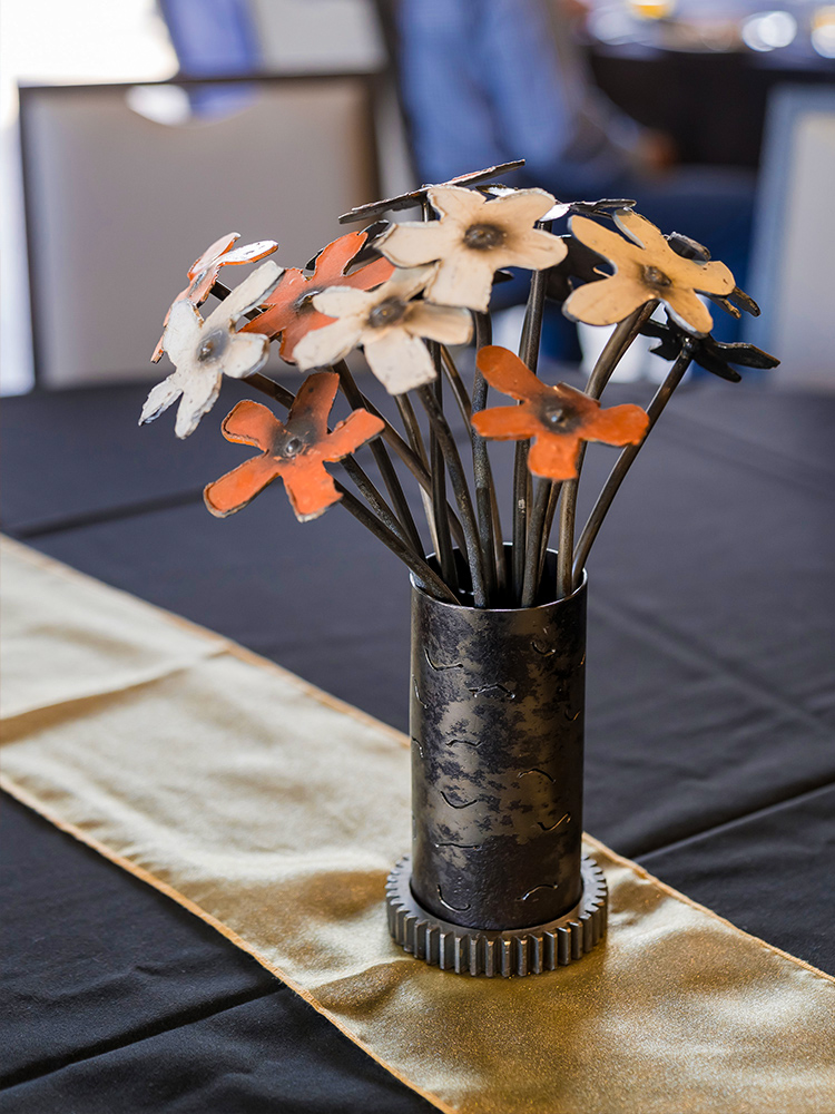 Metal floral centerpiece with orange and white blooms on table