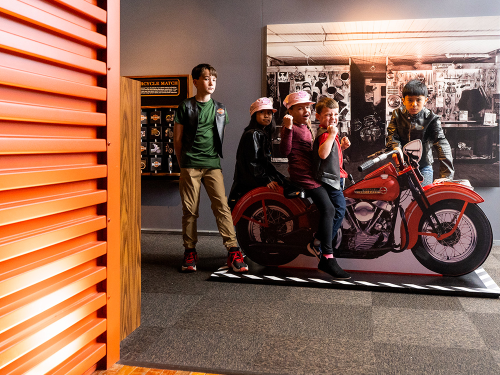 Children posing on vintage motorcycle display in museum exhibit