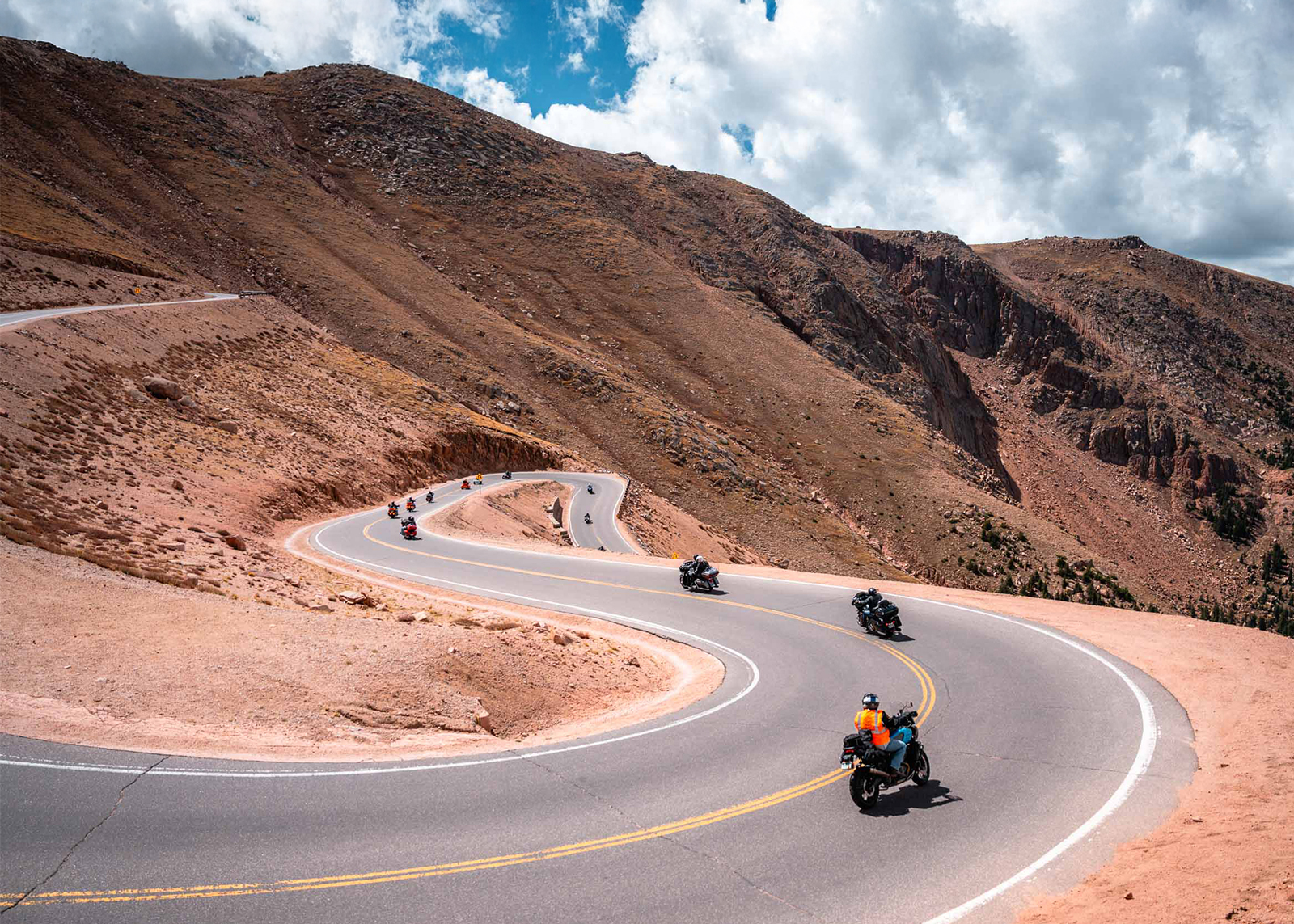 A line of Harley-Davidson motorcycles snake down the winding road from the summit of Pikes Peak.