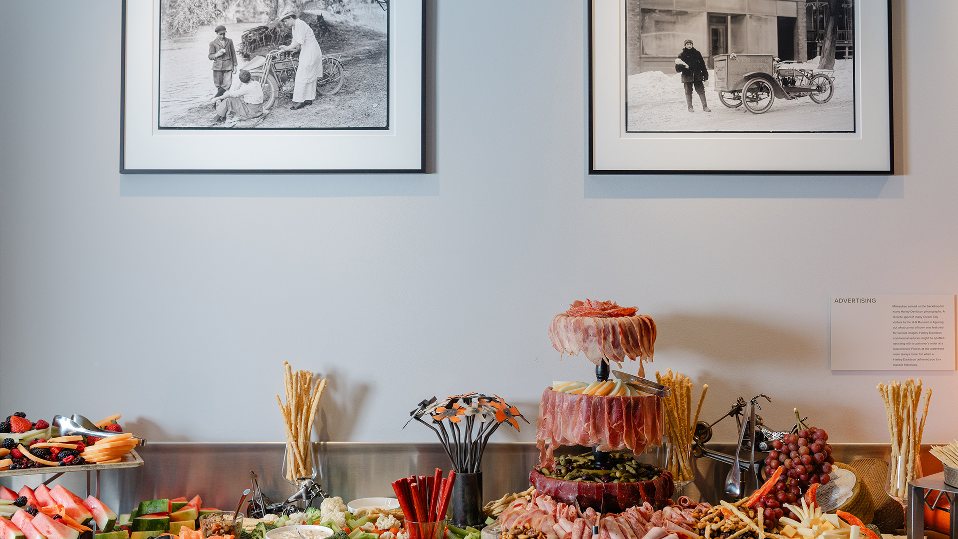 Charcuterie display with meats, cheeses, fruits, and bread in museum setting