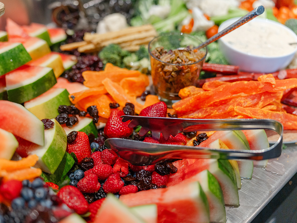 Fresh fruit platter with watermelon, berries, dried fruits, and dipping sauces
