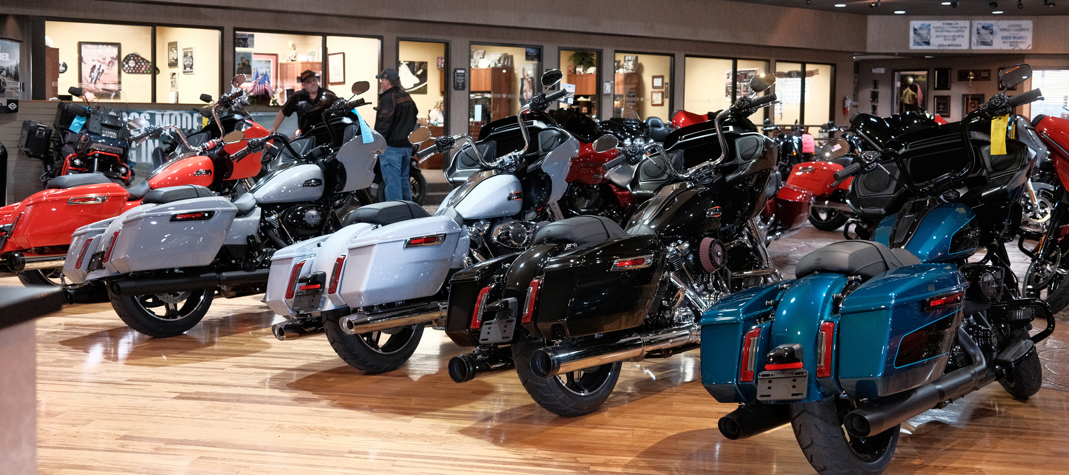 Row of touring motorcycles displayed on polished wood floors inside Bumpus Harley-Davidson