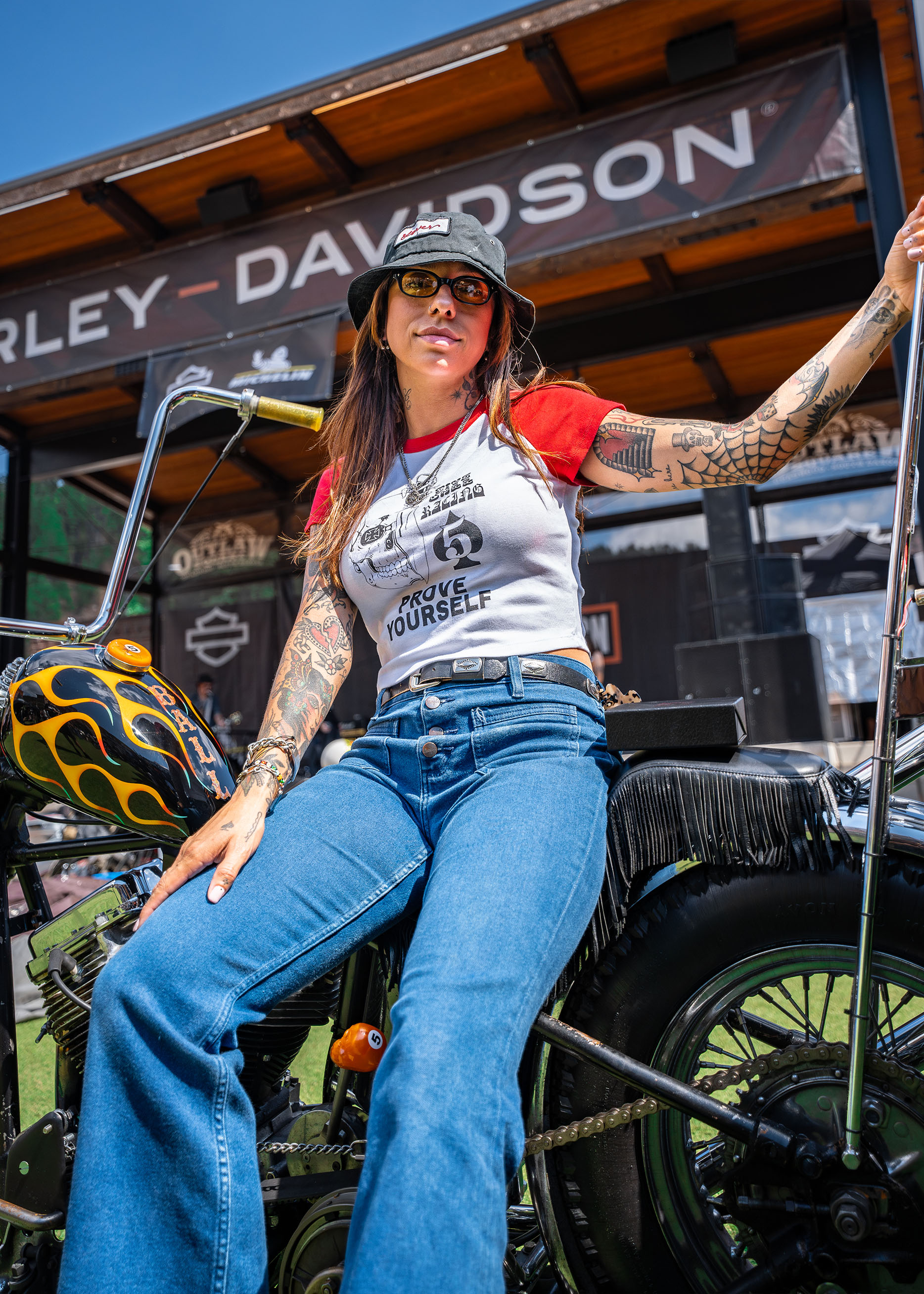 A woman poses on a chopper with a tall sissy bar 