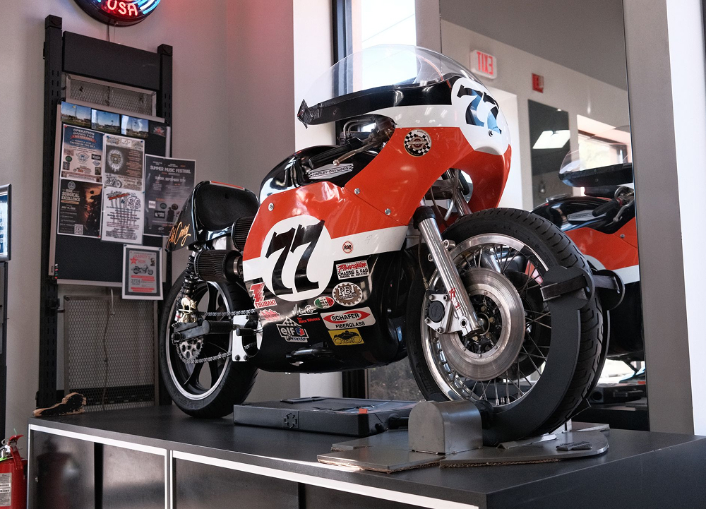Vintage race styled H-D motorcycle on showroom platform with number graphics and display signage nearby