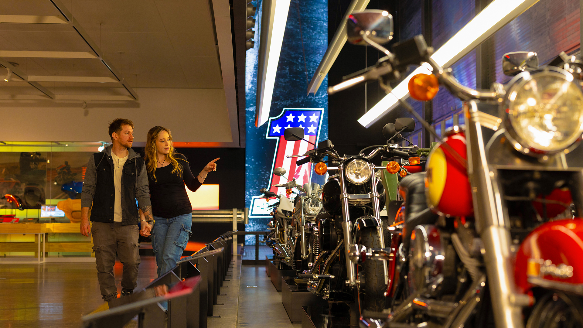 Visitors walking past row of motorcycles in museum exhibit