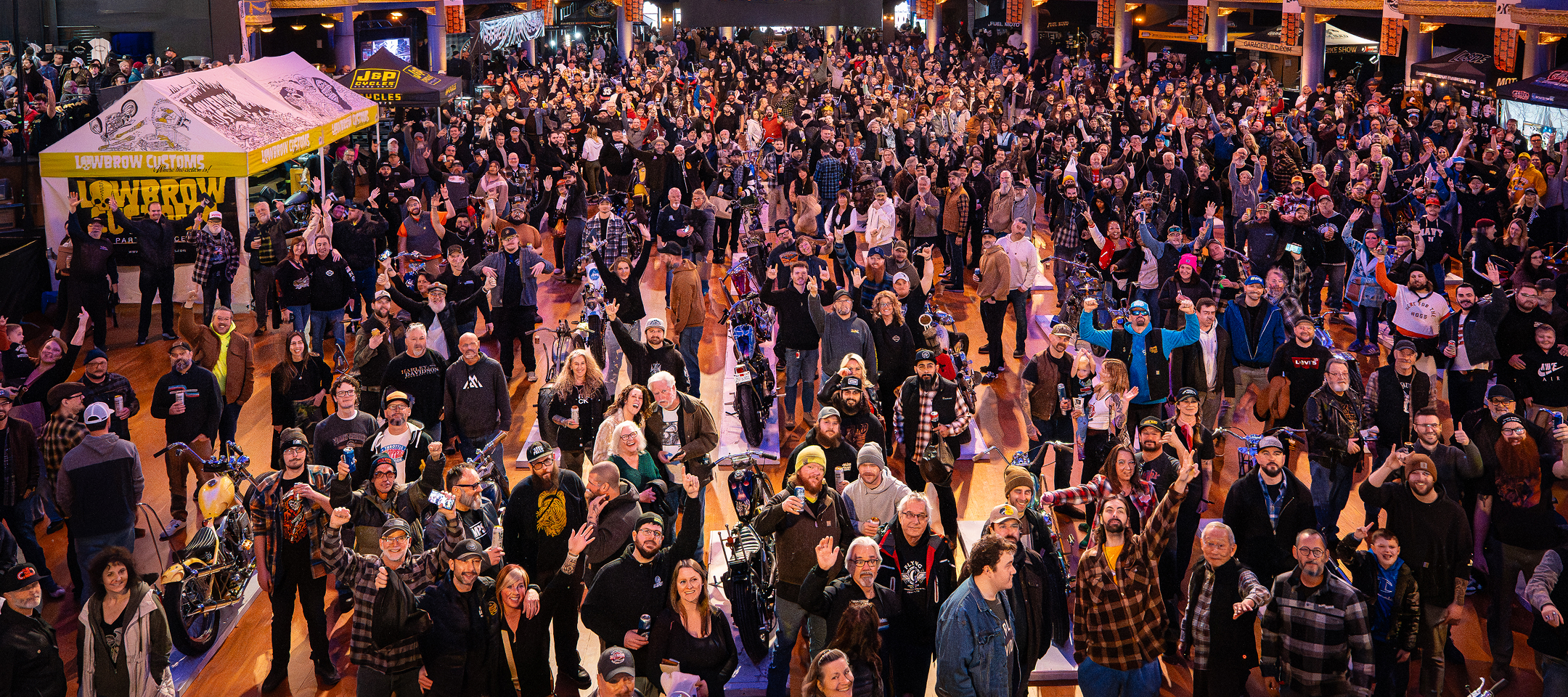 A wide shot of a large crowd waving and cheering to the camera at Mama Tried