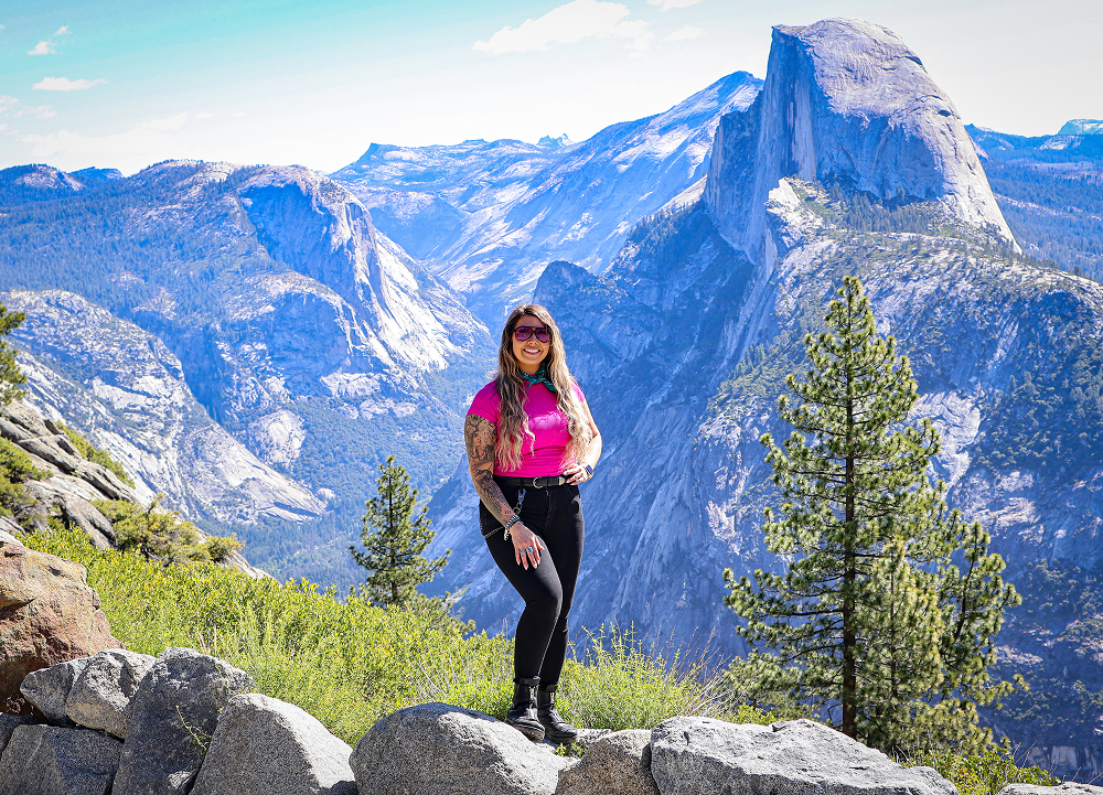 The author stands at a Yosemite overlook with Half Dome rising above the valley and granite peaks beyond