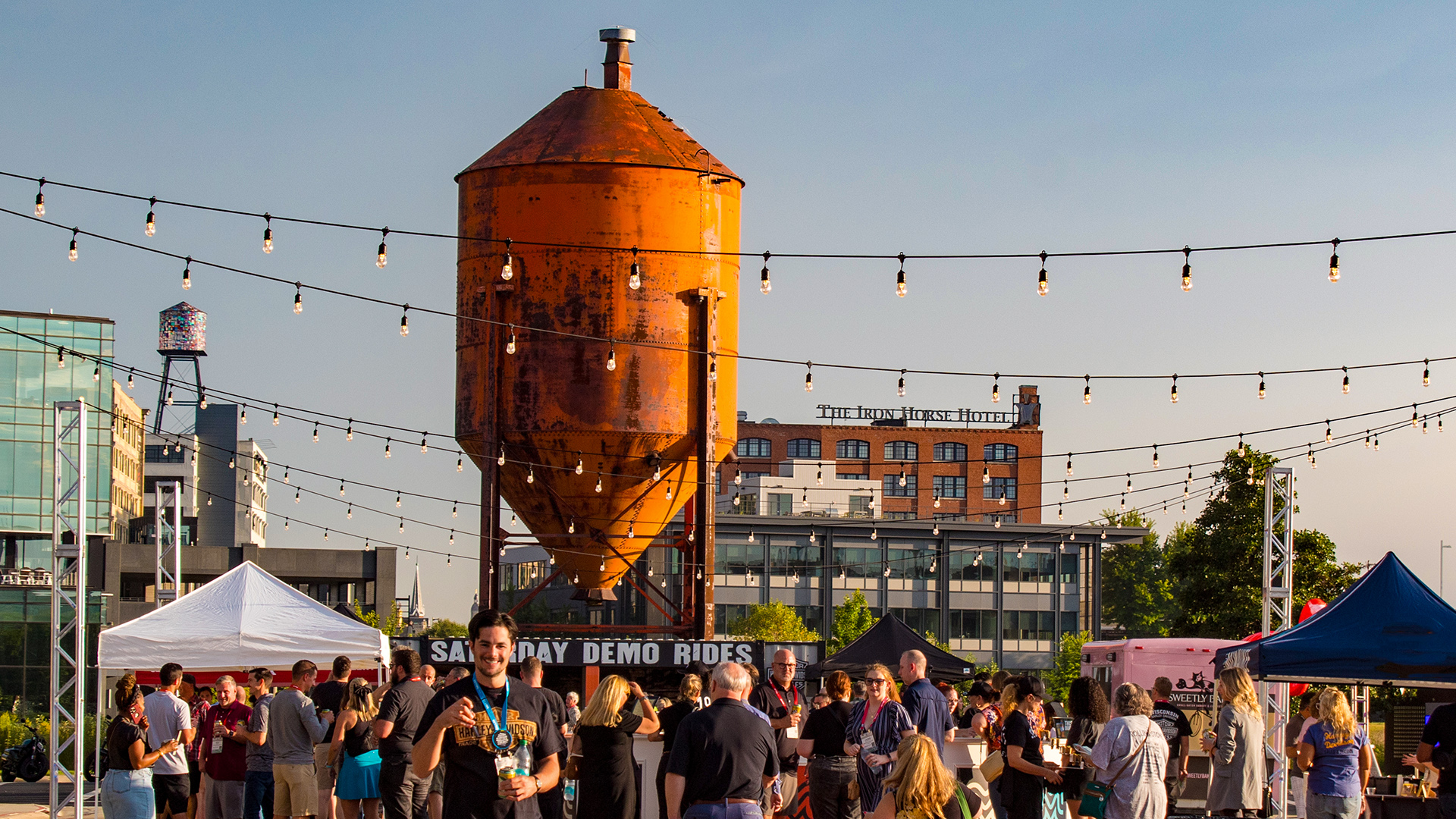 Crowd gathered beneath historic water tower at Harley-Davidson outdoor event