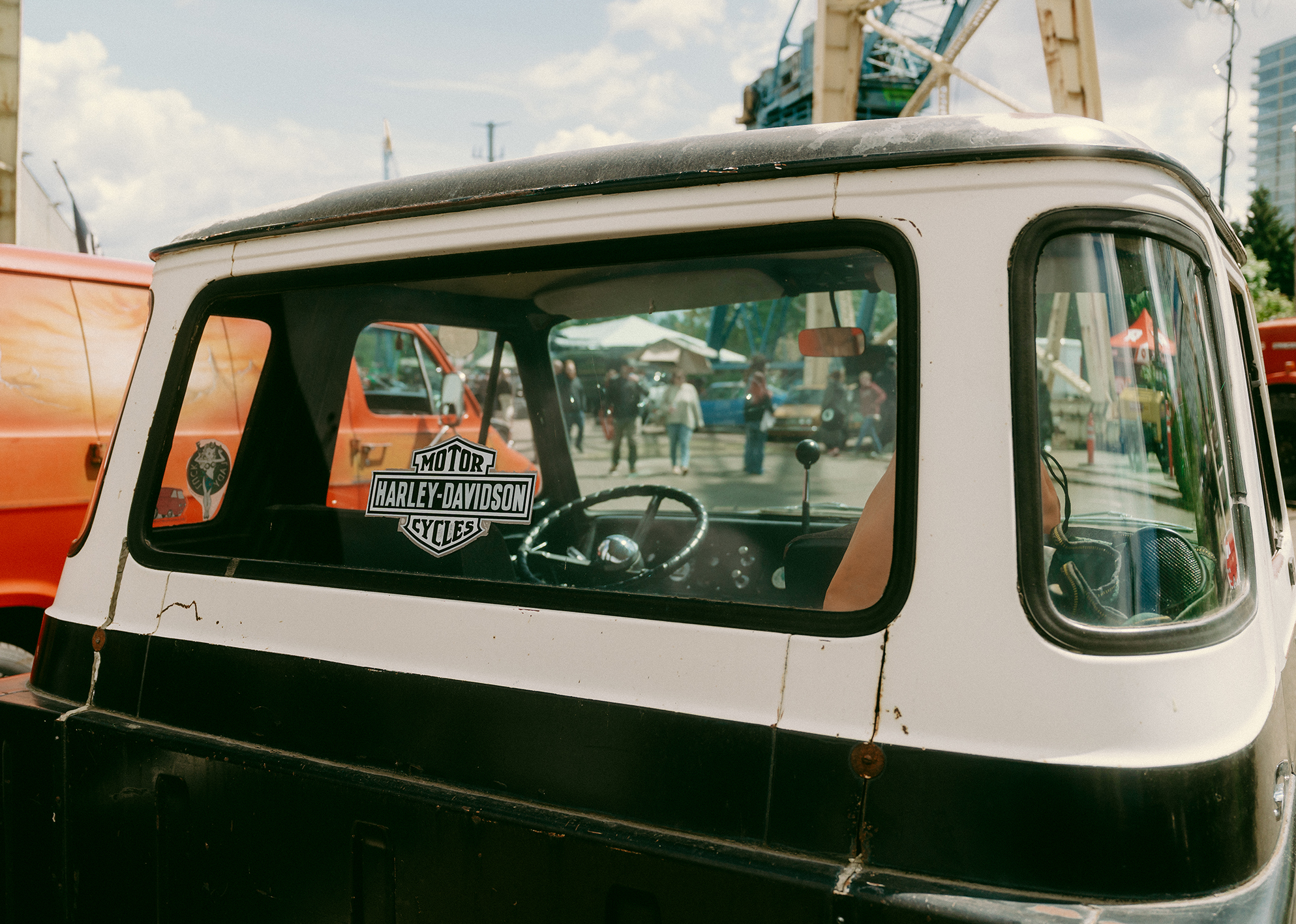 A Harley-Davidson sticker sits on the rearview window of an old black and white pickup.